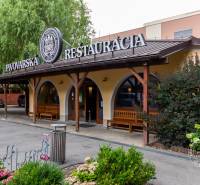 A restaurant with a garden near buildings in a housing estate, green surroundings, black roof.