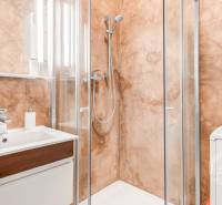 A bathroom with a shower and a mirror in a 2-room apartment, walls with a textured surface.