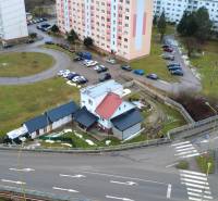 A family house on SNP Street in Považská Bystrica, surrounded by apartment buildings and a parking lot.