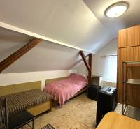 An attic room in a family house with simple furniture and roof beams.
