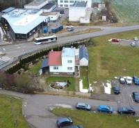 A family house on SNP Street in Považská Bystrica, surrounded by cars and greenery.