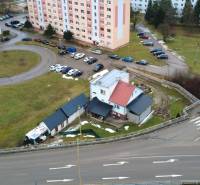A family house in Považská Bystrica on SNP Street surrounded by a parking lot and apartment buildings.