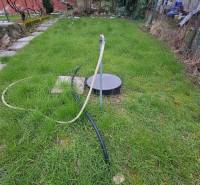 A garden by the cottage in Šemša, a lawn with a well and a hose.