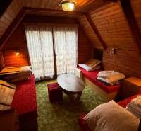 Interior of a cabin with wooden paneling, three beds, and a round table.