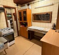 A kitchen in a cottage with a gas stove, wooden decor, and kitchen cabinets.
