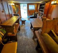 Interior of a cabin with wooden tables and benches, view of the garden.