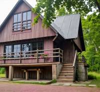 A wooden cottage in Kováčová surrounded by greenery with blooming flowers on the terrace.