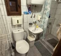 A bathroom in a cabin with a shower, sink, toilet, and tiled walls.