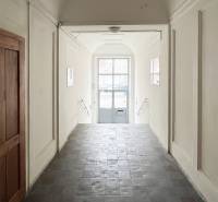 A corridor with tiles and white walls leads to a glass door on Vajnorská Street.