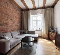 The living room in the 2-room apartment with a brick wall, Vajnorská, Bratislava, offers a comfortable sofa and a coffee table.