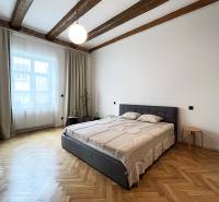 A bright bedroom with wooden beams, a comfortable bed, and parquet flooring on Vajnorská Street.