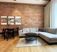 Living room with a brick wall, sofa, table, and paintings; bright space on Vajnorská Street, Bratislava.