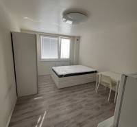 Studio apartment with a bed, wardrobe, table, and floor with a wooden decor.