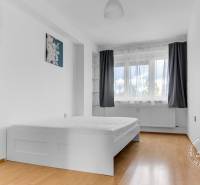 A bright bedroom with a bed, curtains, decoration, and a wooden decor floor in a 3-room apartment.