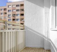 A balcony in a 3-room apartment with a view of a block of flats, floor with wood decor.