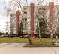An apartment building with a parking lot surrounded by greenery at Karpatské Square in Bratislava - Rača.