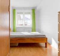 Bedroom in a 3-room apartment with a bed, green curtains, and a wooden decor floor.
