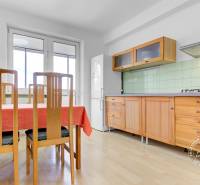 A kitchen in a 3-room apartment with a table, chairs, and a floor with a wooden decor.