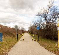 Bicycle path on Karpatské Square in Rača with traffic signs and barrier.