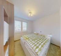 Bedroom in a 4-room apartment with a bed, built-in wardrobe, and floor with wooden decor.