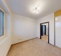 A room with a built-in wardrobe and carpet in a 4-room apartment, light coming through the blinds.