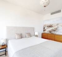 Bedroom in a 3-room apartment with a large bed, a painting, and a wooden dresser.