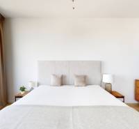 A room in a 3-room apartment with a large bed, a dresser, and a decorative painting.