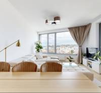 Living room of a three-room apartment with a light-colored sofa, large windows, and a view of the city.