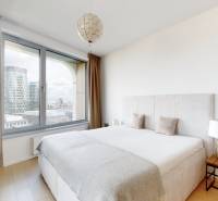 Bedroom in a 3-room apartment with a large window, curtains, and a floor with a wooden decor.
