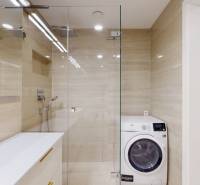 A bathroom with a shower and a washing machine in a 3-room apartment.