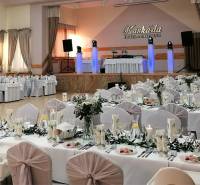 A banquet hall prepared for a wedding reception, tables adorned with white tablecloths.