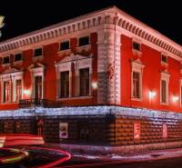 A brightly lit hotel building with a red facade in Poprad. Hotels and guesthouses.