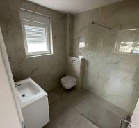 Bathroom in a 3-room apartment with a sink, toilet, and shower enclosure with a glass wall.