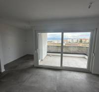 An empty room with large windows in a 3-room apartment, overlooking the balcony.