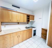 A kitchen in a 2-room apartment with ceramic tiles and wooden cabinets.
