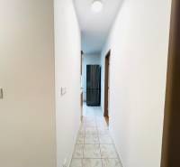 A hallway with tiles leading to the rooms in a 2-room apartment.