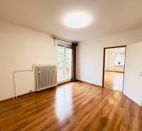 A room in a 2-room apartment with large windows and a floor with a wooden decor.