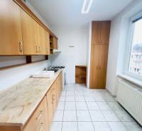 A kitchen with wooden decor and white tiles in a 2-room apartment.