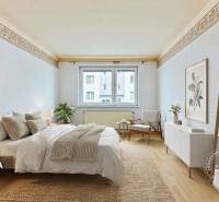 Bedroom with a bed, carpet, armchair, decorations, wooden-patterned floor.