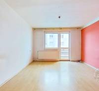 A room in a three-room apartment with a wooden decor floor and a balcony.