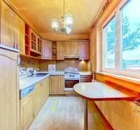 A kitchen with wooden cabinets and a wooden decor floor in a 3-room apartment.