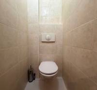 A toilet with white tiles and a built-in toilet in a 3-room apartment.