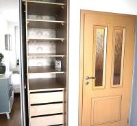 An open wardrobe with shelves and drawers in a 2-room apartment, floor with wood decor.