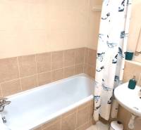Bathroom in a 2-room apartment with a bathtub, sink, and bathroom tiles.
