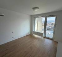 A studio apartment with a wooden floor design and a balcony view of the city.