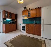 A kitchen with wooden cabinets and green tiles in a family house.