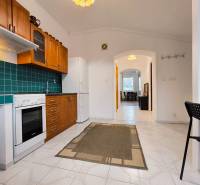 A kitchen in a family house with white tiles, wooden decor, and blue tiles.