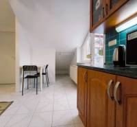 A kitchen in a family house with wooden cabinets, a table, and two black chairs.