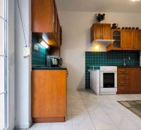 A kitchen in a family house with wooden cabinets, green tiles, and a white stove.