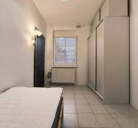 A bedroom in a family house with a bed, a built-in wardrobe, and tiles.